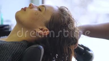 美发师在美容院用专业吹风机吹干漂亮女孩的头发。专业美发师使用